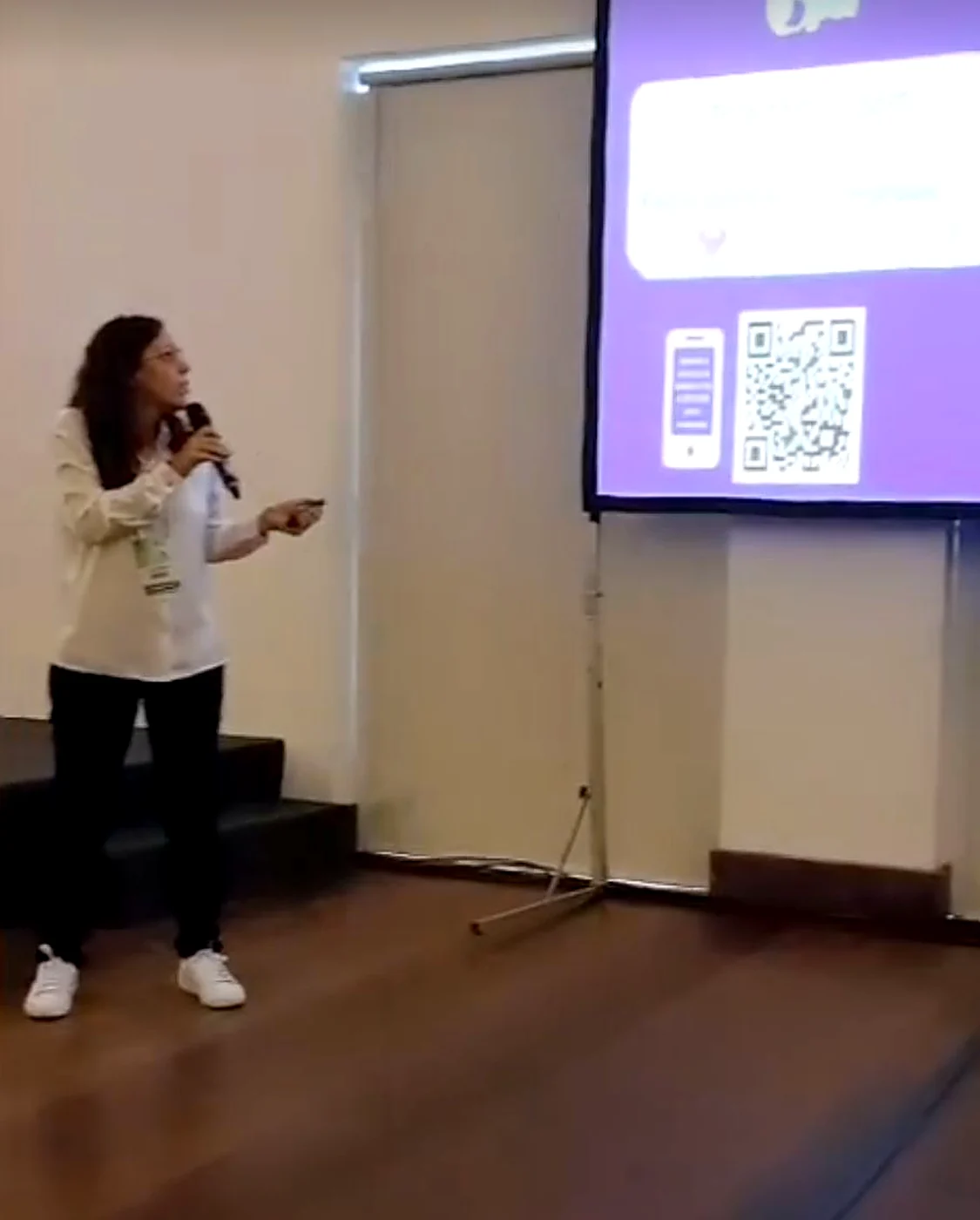 Tali Vasquez em palestra, com código QR no ecrã gigante